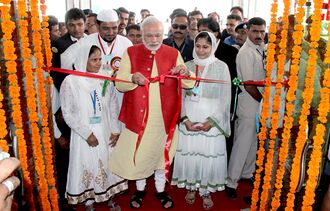 Modi unties a ceremonial red ribbon before a crowd of onlookers
