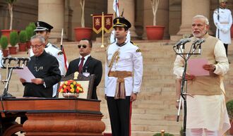 Modi reading from a paper into a bank of microphones